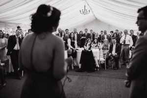 Standing Woman Giving Speech To Group of Seated Wedding Guests