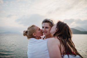 Bride getting kissed by her bridesmaids on a trip